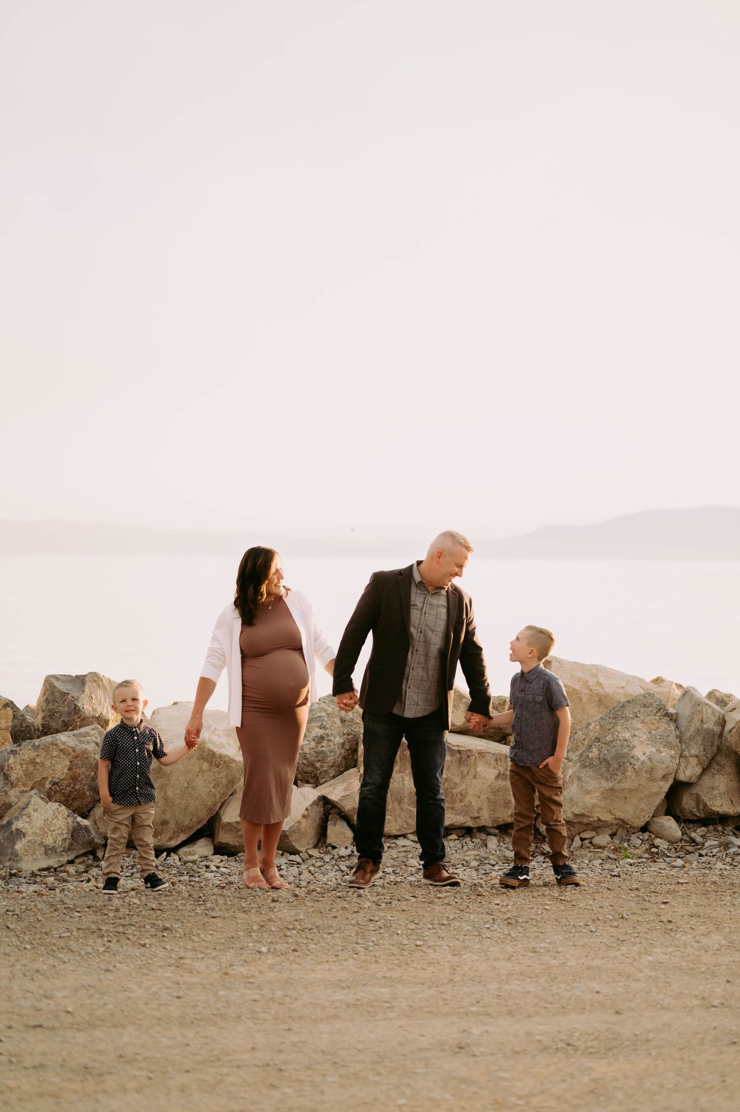 A family of four stands together on rocky terrain against a misty mountain backdrop.