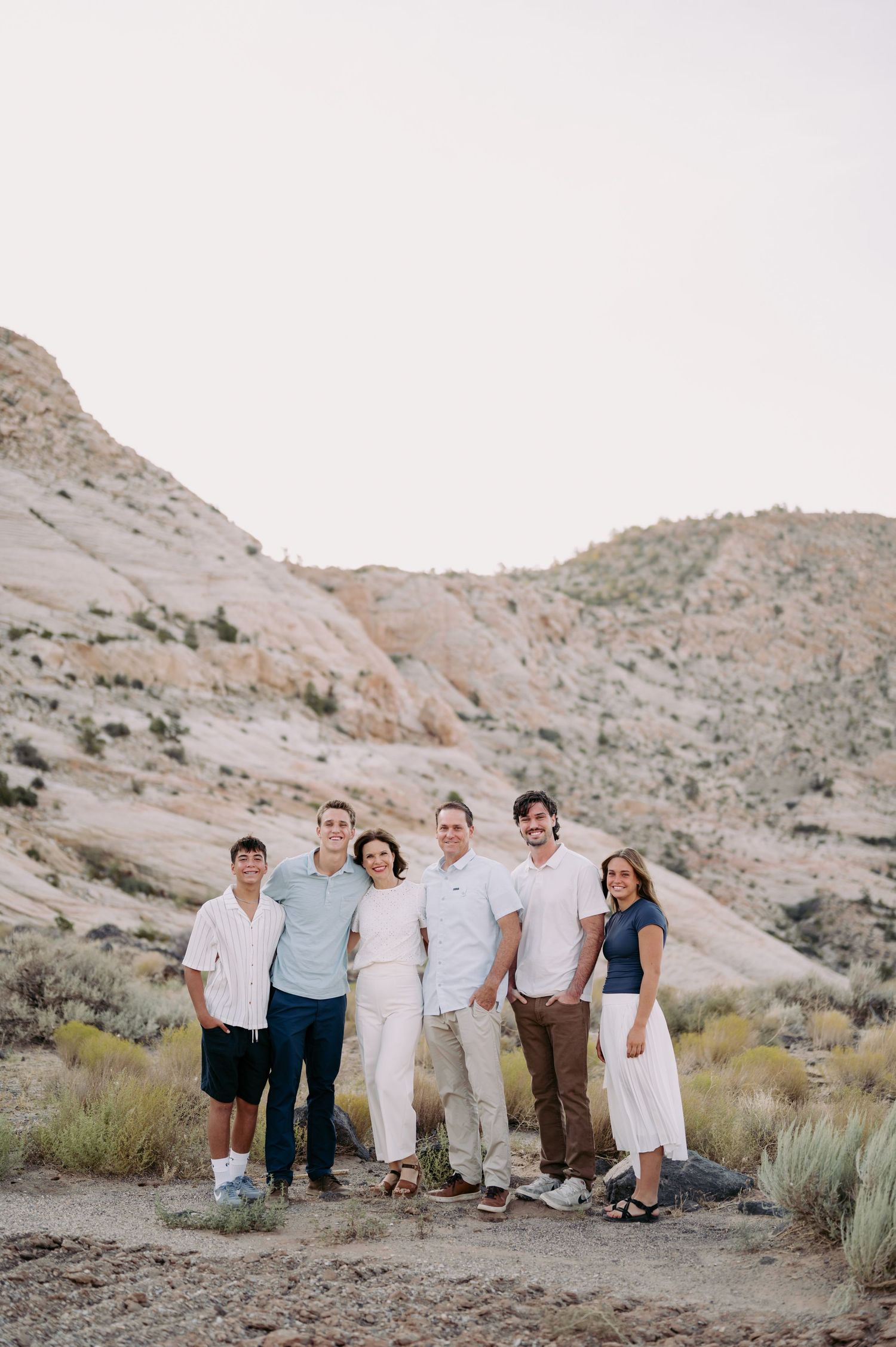 A group of people stand together on a desert hillside during golden hour.