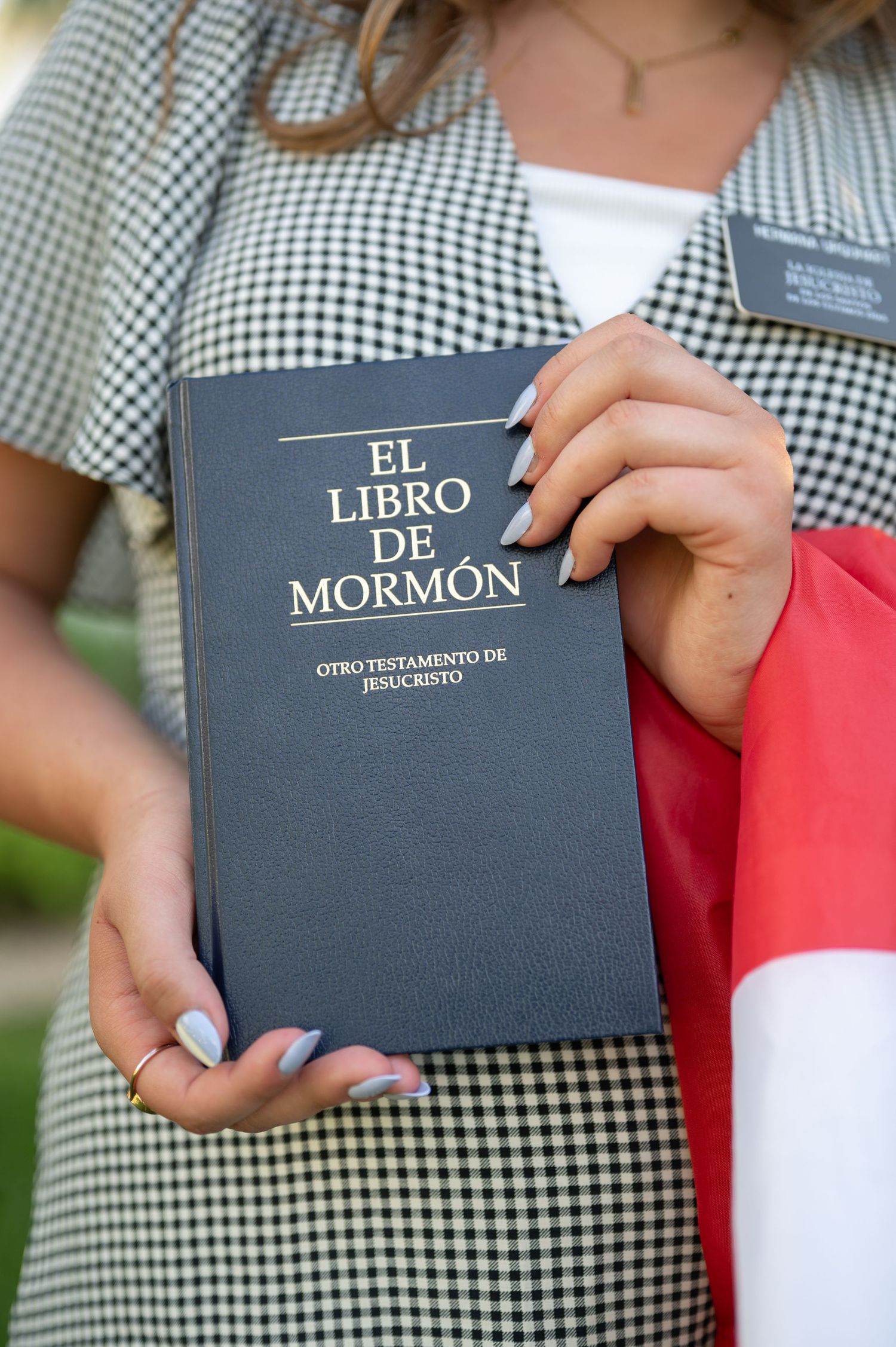 A close-up shot of hands holding El Libro de Mormon in a black cover.