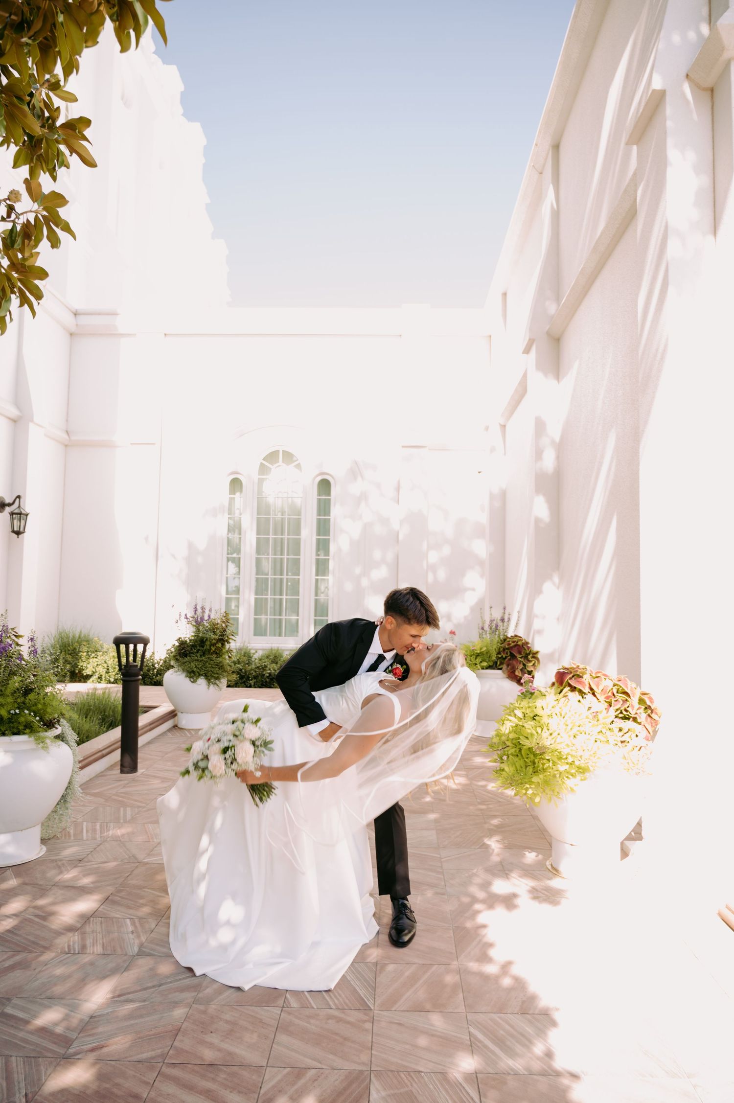 A romantic dip pose between newlyweds on a sunny temple terrace.