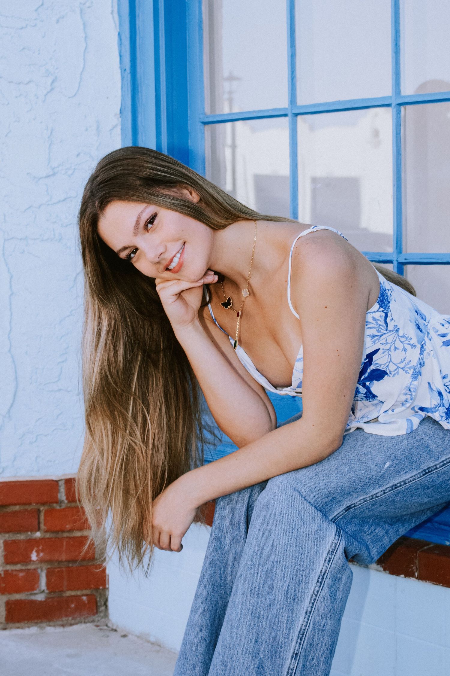 Senior Girl Poses in Front of Blue Wall Located in Oklahoma's Paseo Arts District