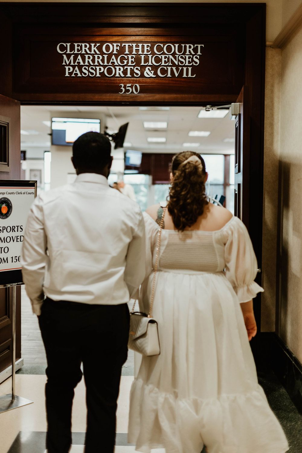 A couple walks down a hallway towards the Clerk of the Court and Marriage License office.