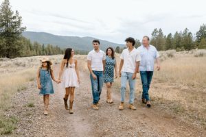 A group walks together on a dirt path through a scenic mountain landscape with tall pine trees.
