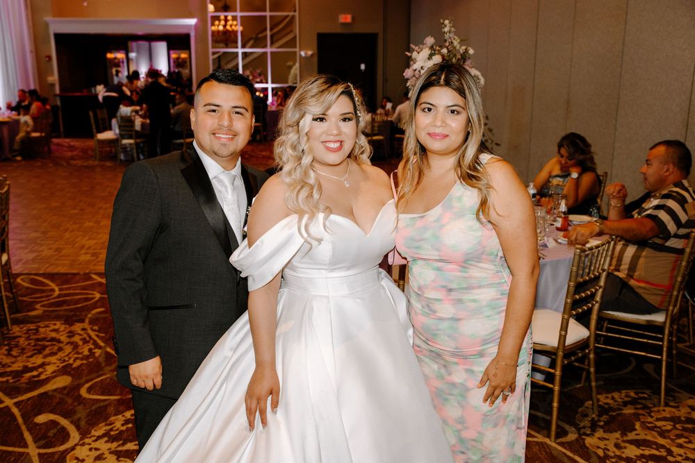 Wedding party celebrates and dances together during reception in elegant ballroom setting.