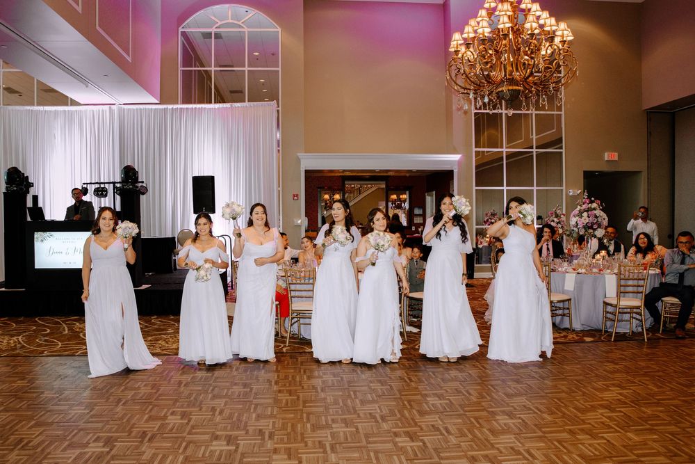 A wedding reception scene shows people in white dresses and formal attire dancing in an elegant ballroom with chandeliers.