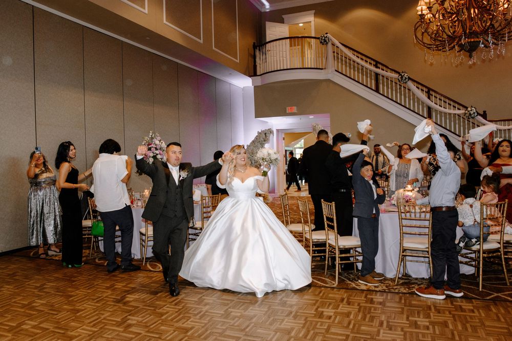 Wedding guests dance and celebrate at an elegant reception venue with warm lighting and crystal chandeliers.