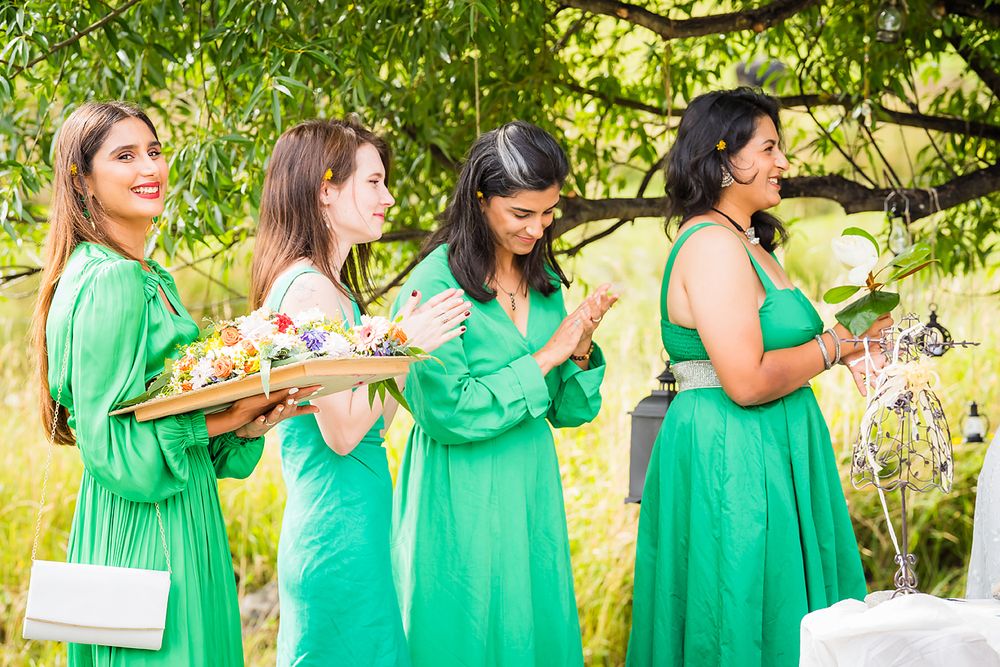 Bridesmaids in emerald green dresses pose together in a creative sequence outdoors under tree branches.