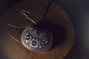 An ornate silver vintage necklace with gemstones photographed on dark surface.