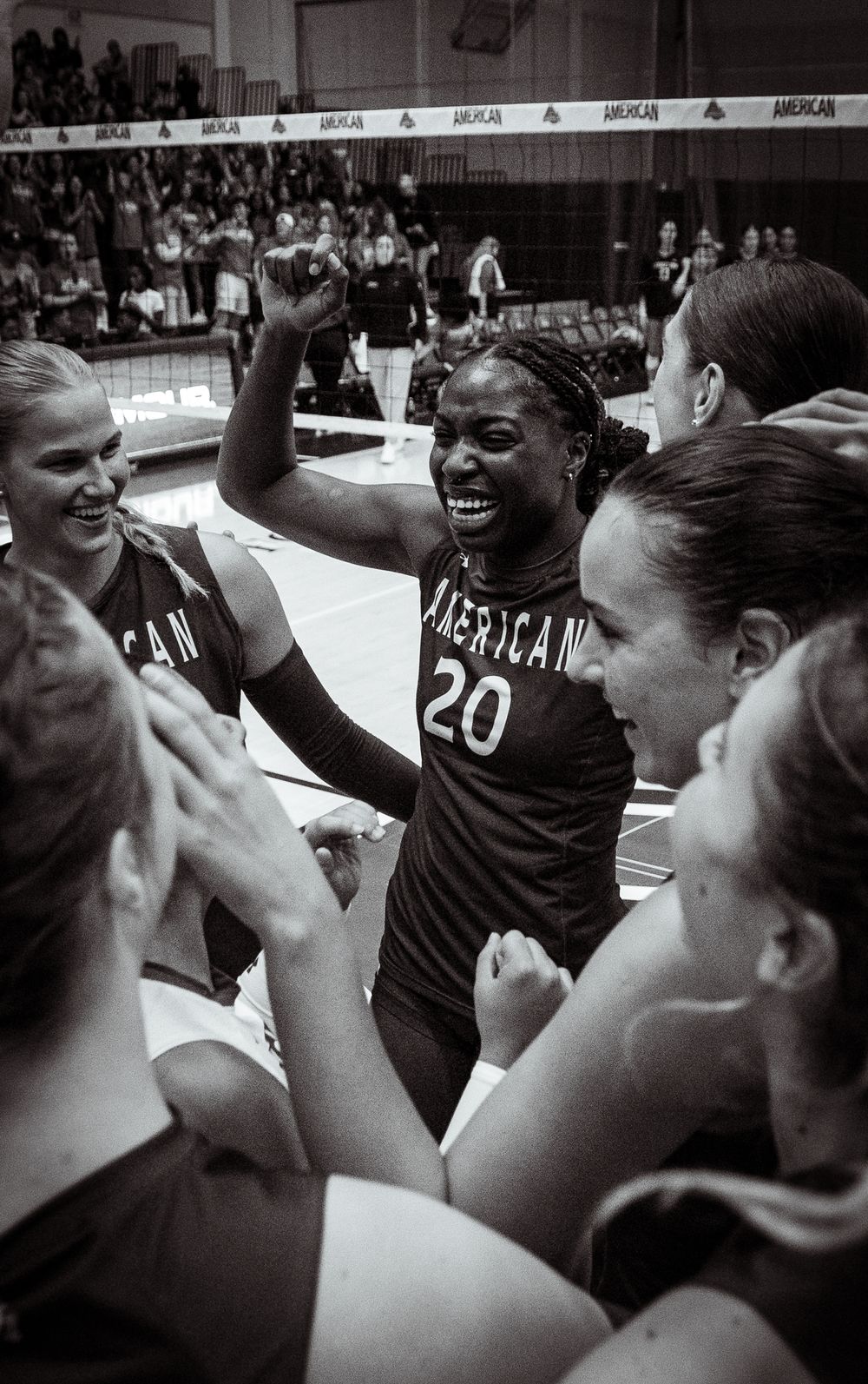 Basketball team huddles together in celebration showing team unity and excitement in black and white photograph.