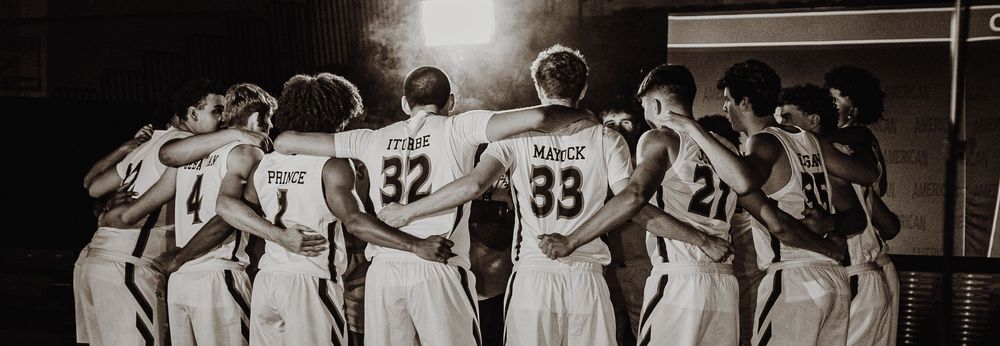 Basketball team huddles together in black and white vintage style photograph.