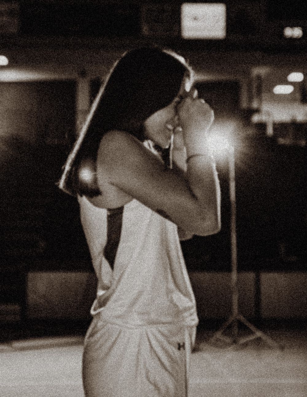 Basketball player in white uniform prepares for game in dramatic lighting.