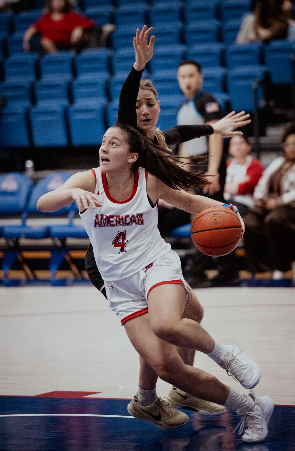 Basketball player drives to basket in white American uniform during intense game action.