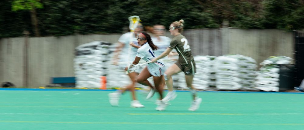Motion blurred athletes running on green field during sports match.
