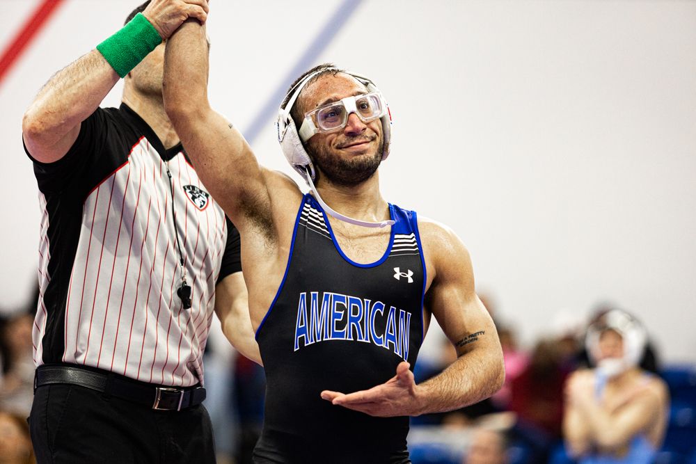 Athlete celebrates victory with raised arm during sporting event.