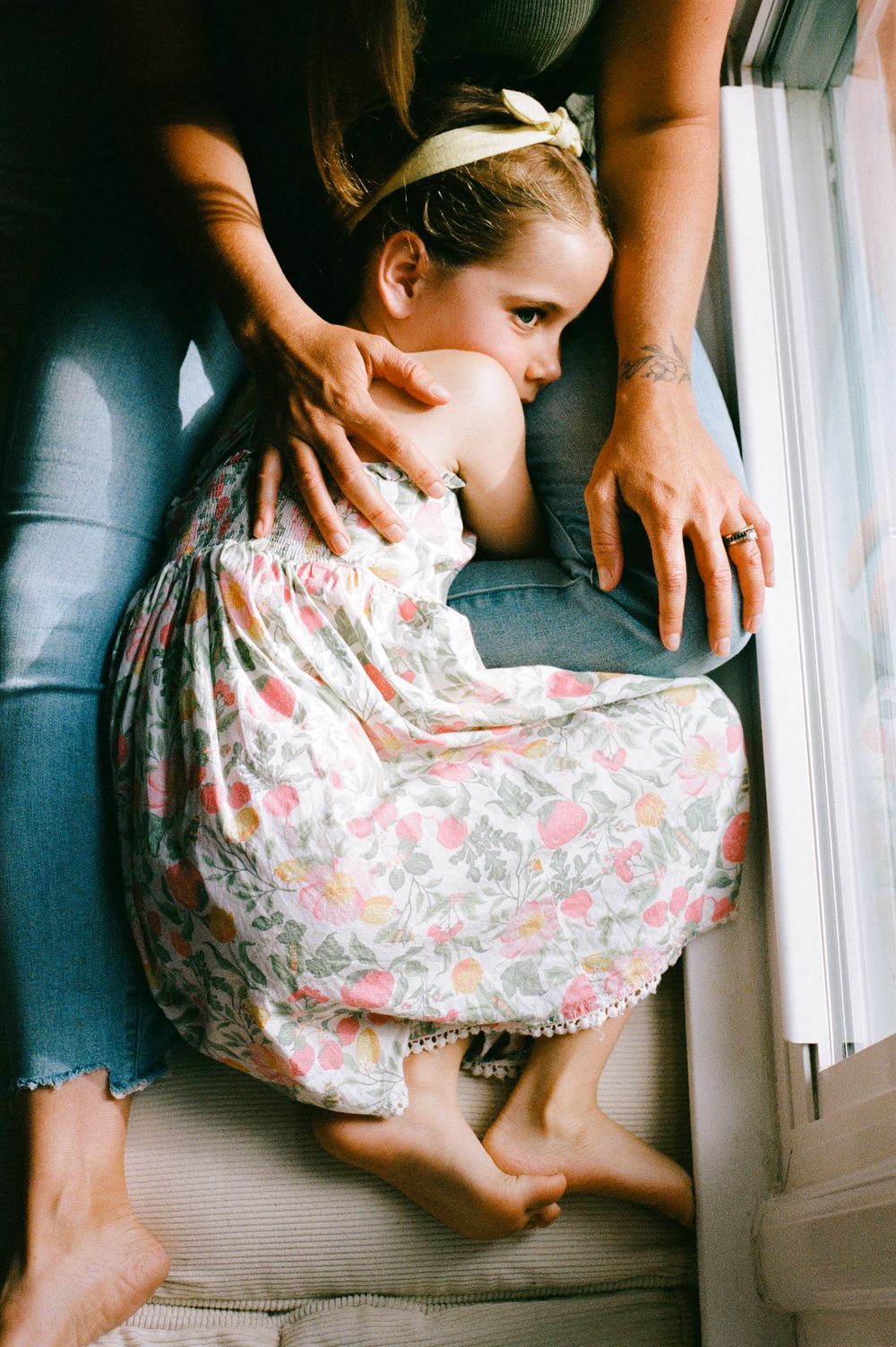 A series of soft vintage-style photos show a small child resting on a couch by a window in a floral dress.