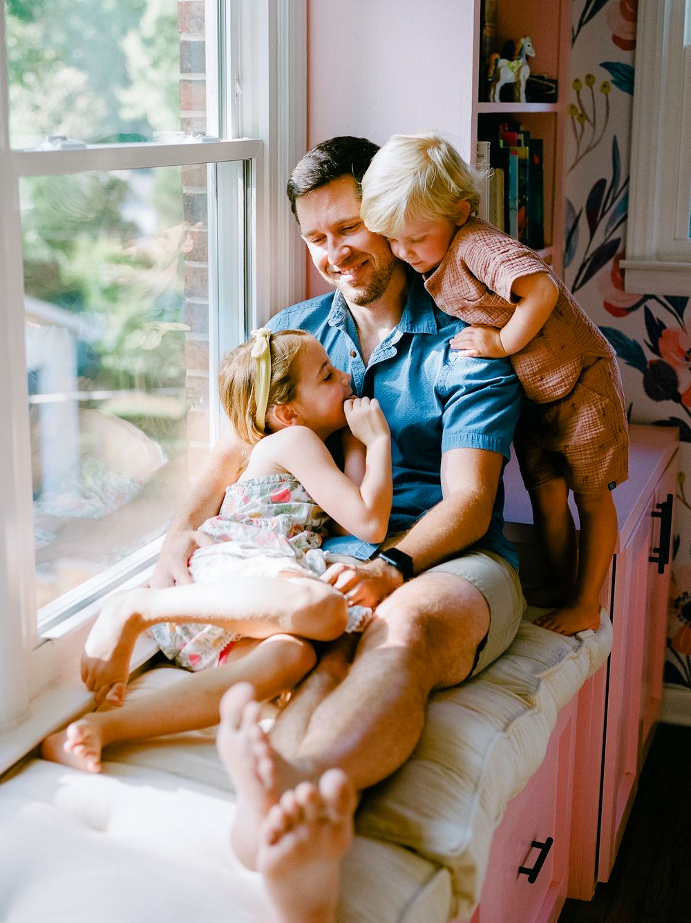 Family sharing intimate moments while relaxing together by window.