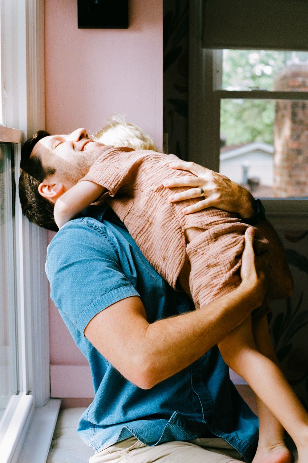 Series of artistic photos showing emotional moment near window with blue shirt and tan top.
