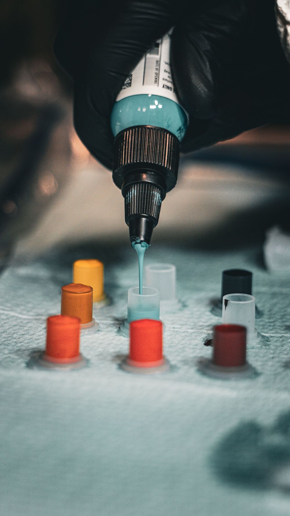 Multiple tattoo ink colors being prepared in small caps for application.