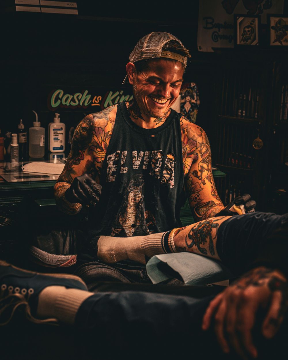 Tattoo artist working in dimly lit studio environment.