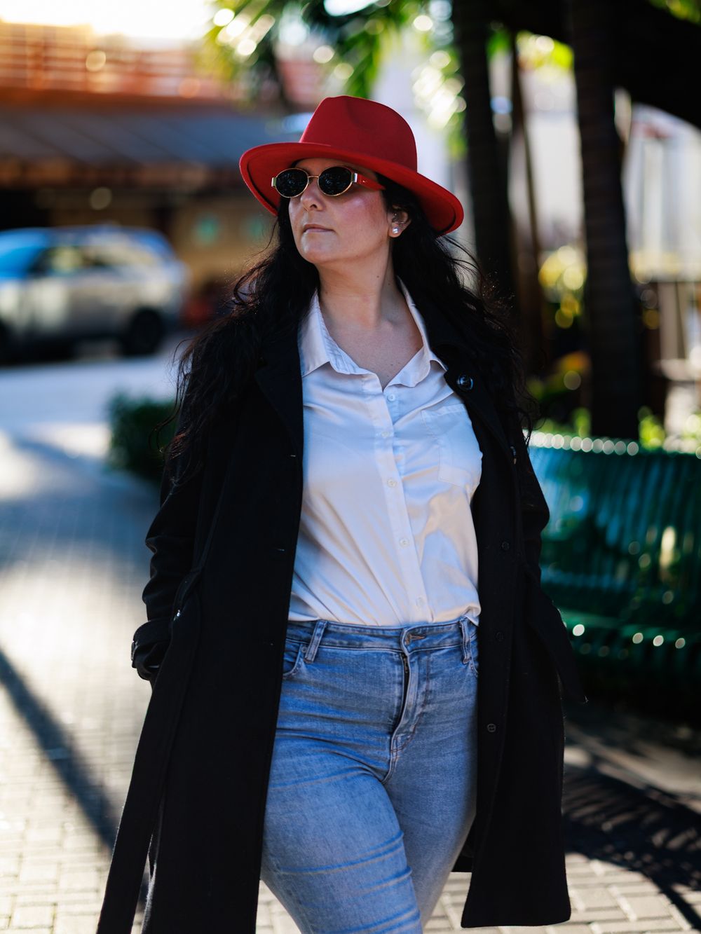 Stylish outfit featuring a black coat, white shirt, and blue jeans in an urban setting.