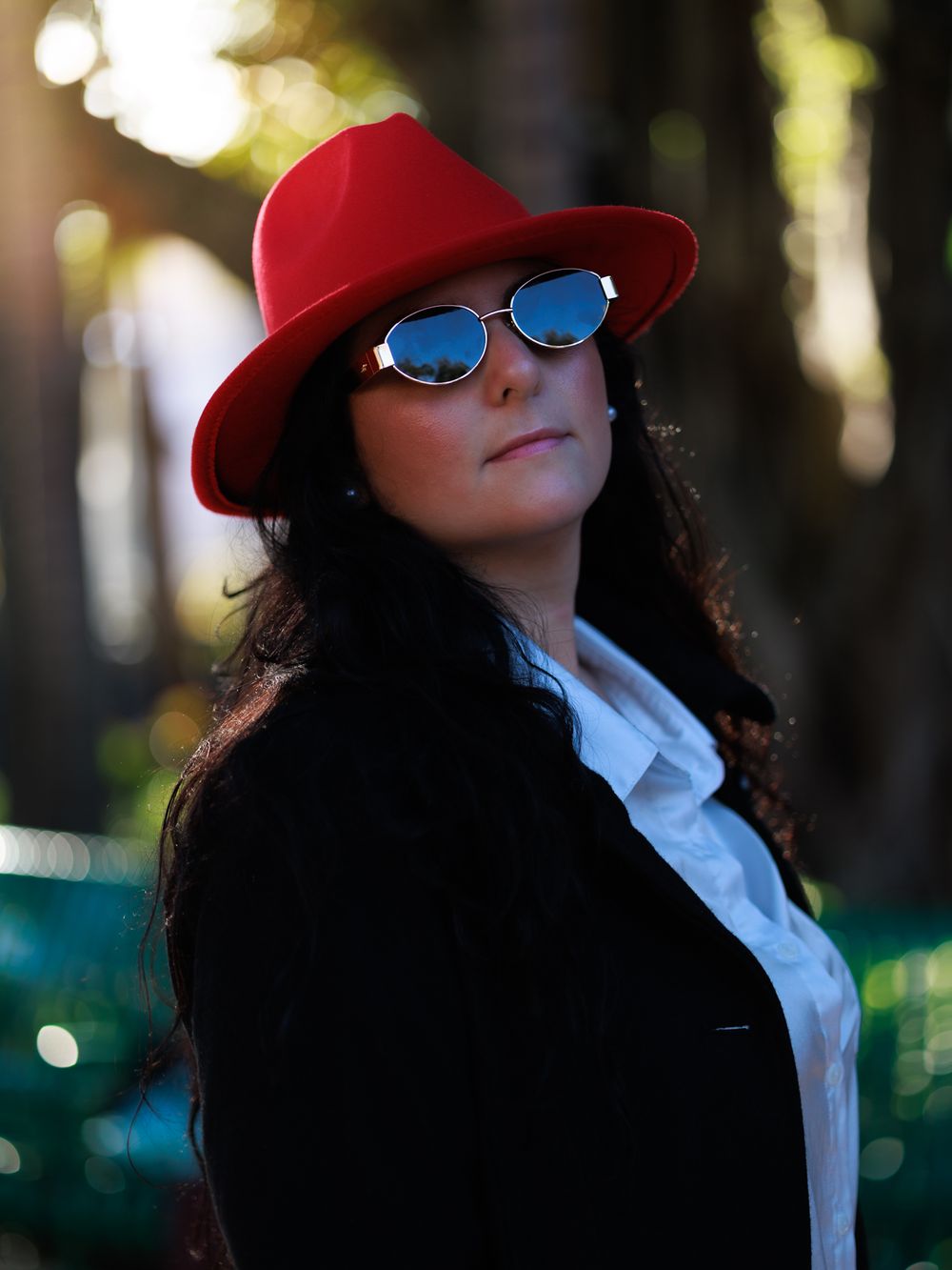 Fashion portrait featuring a red hat and sunglasses against a bokeh background.