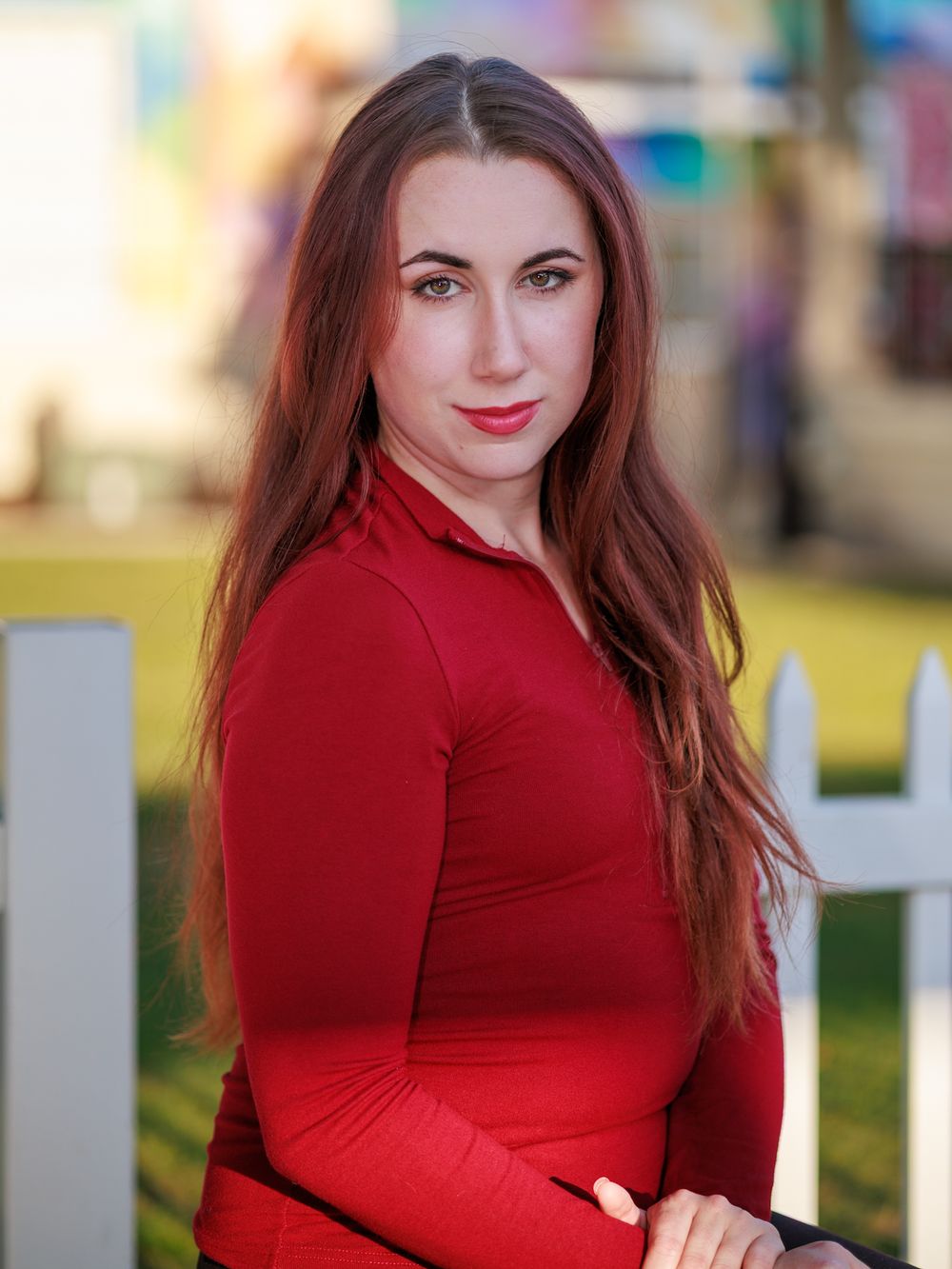 Outdoor portrait series featuring a red fitted top styled against a colorful blurred background.