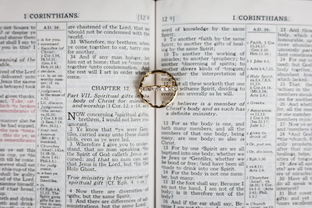 Wedding rings displayed in the Bible page showing text from 1 Corinthians with handwritten notes and annotations in the margins.