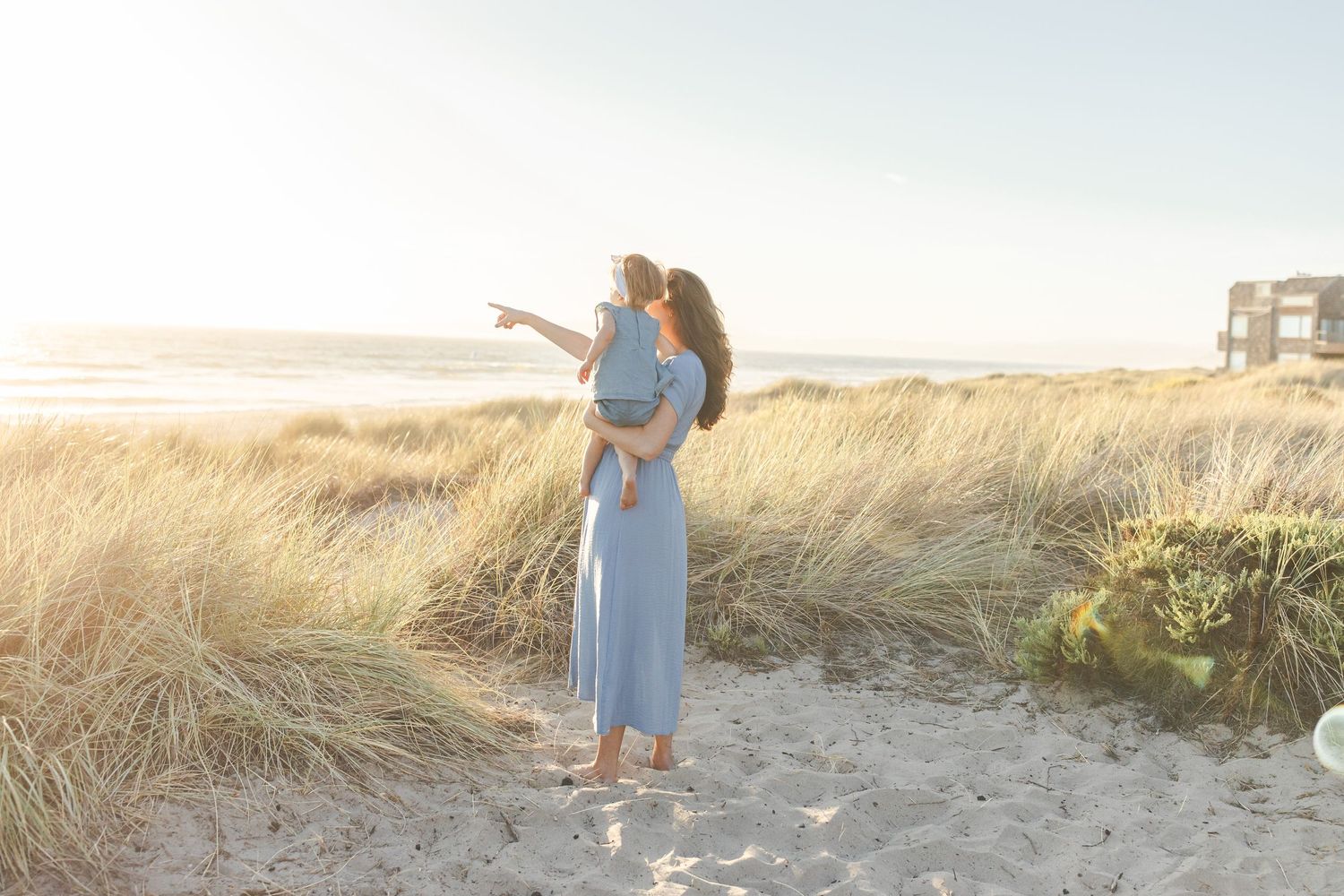 A couple shares a romantic embrace at sunset on a sandy beach path surrounded by windswept dunes and golden light.Film by Chelsee Rawe Photo
