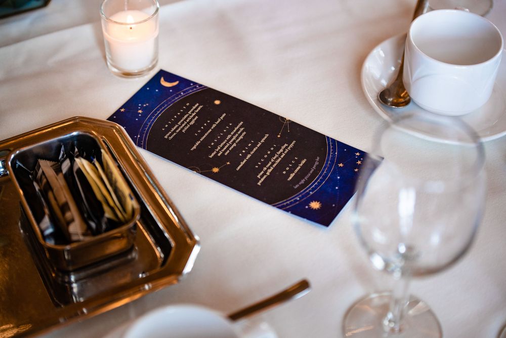 A table setting featuring a collection of lit candles, menu cards, and elegant glassware for fine dining.