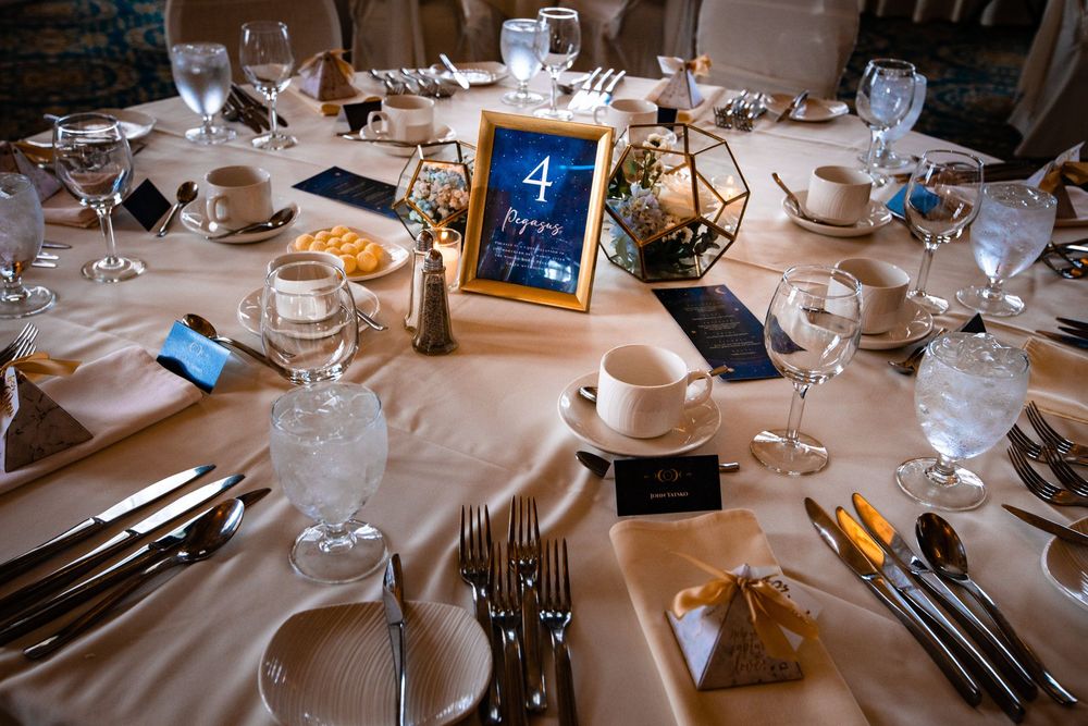Elegant table settings with white linens and wine glasses arranged for a formal dining event at a restaurant.