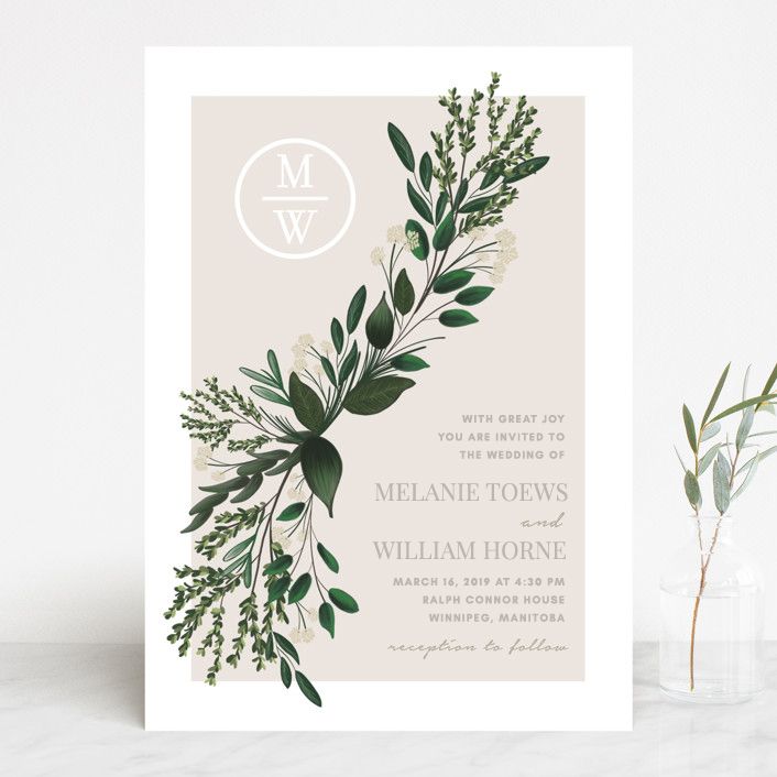 Elegant wedding invitation design with green botanical leaves and monogram logo on light beige background.