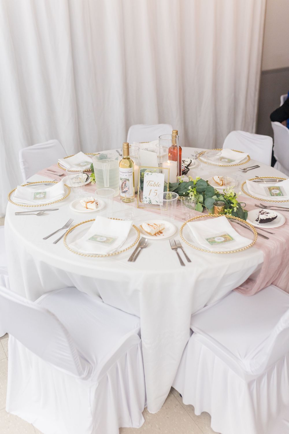 Elegant wedding reception table setting with white linens, gold accents, and delicate floral centerpieces.