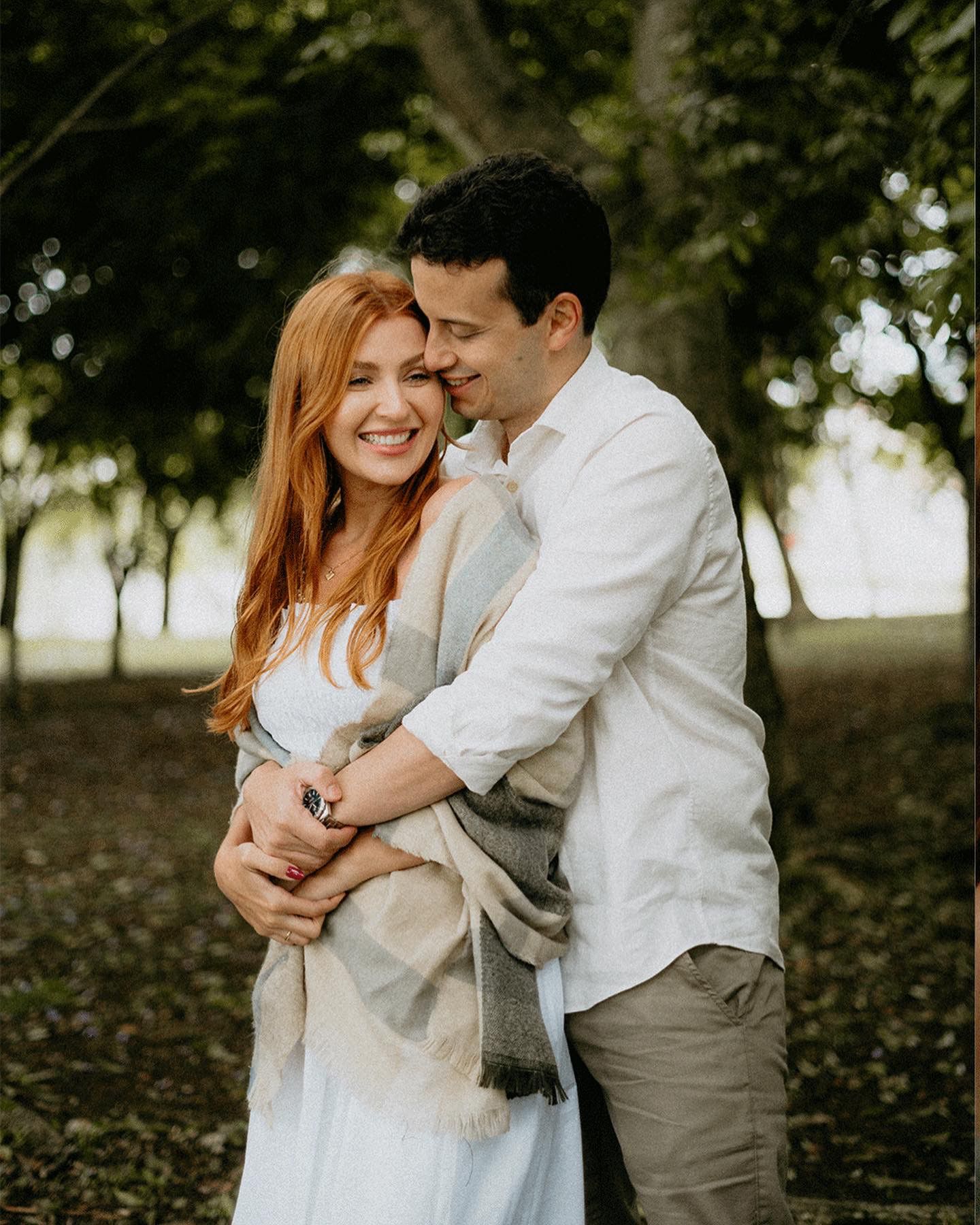 A couple shares an intimate moment while embracing in a park setting.