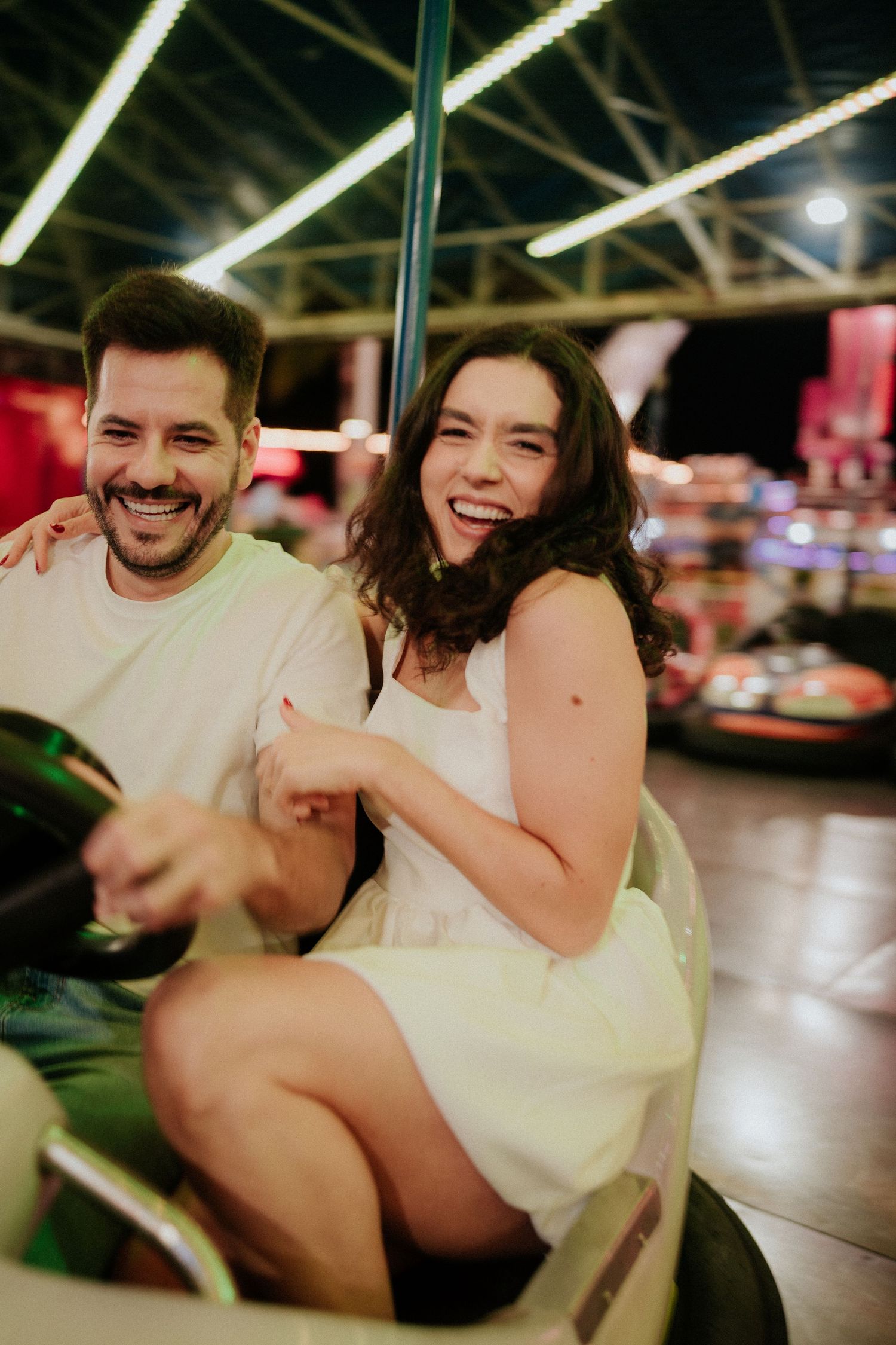 Playful couple sharing laughs while riding an amusement park attraction.