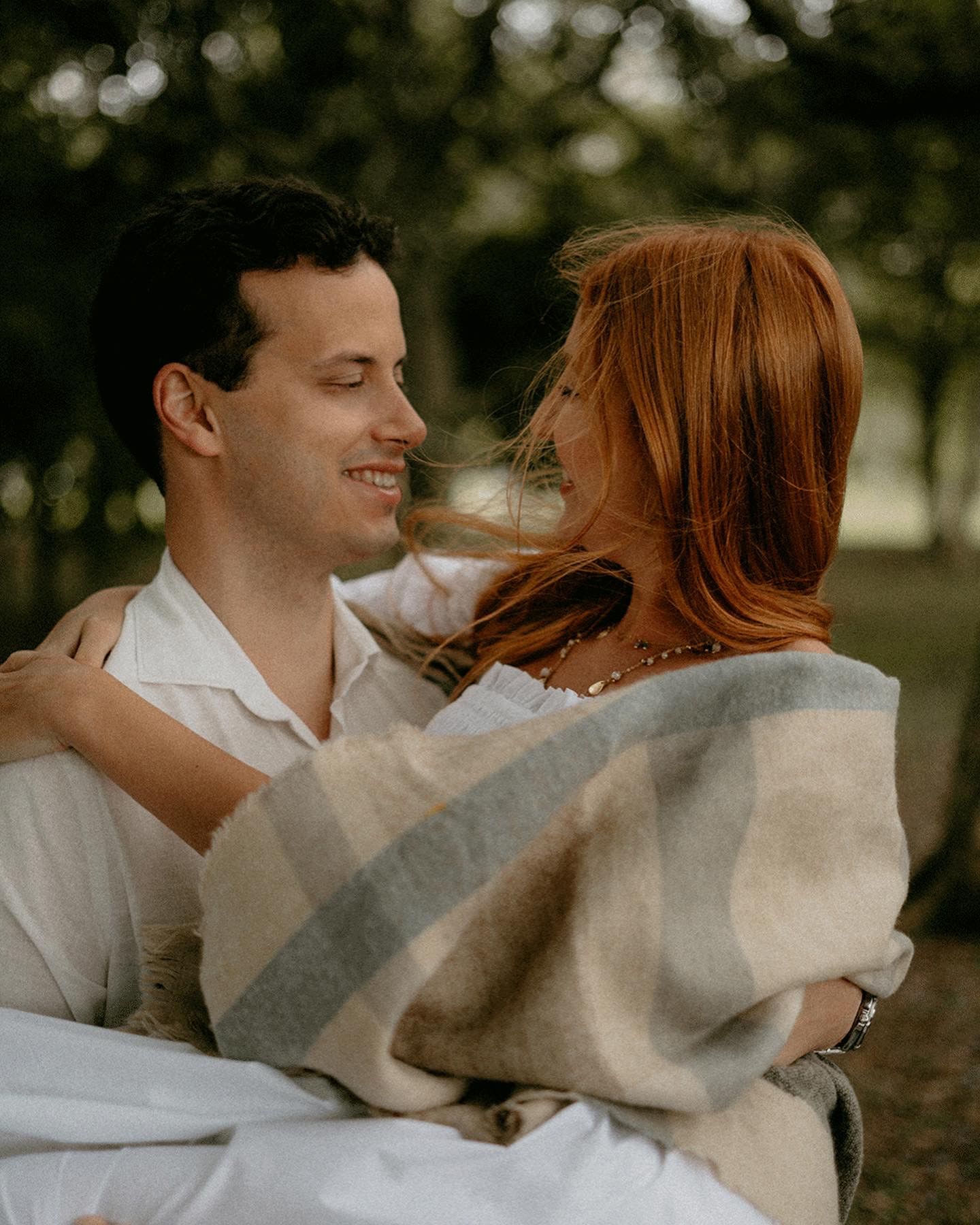 A romantic couple embraces outdoors in soft natural lighting.