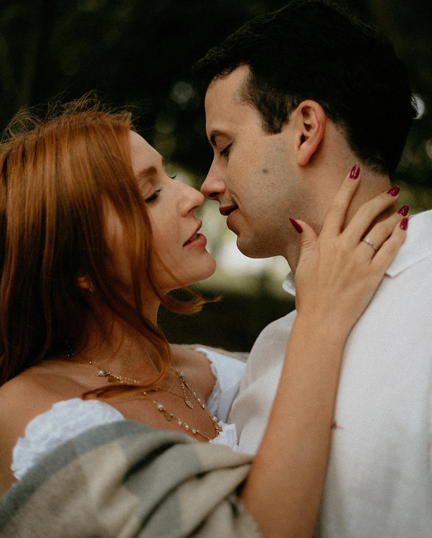 A tender moment between a couple as they draw close for a kiss outdoors.