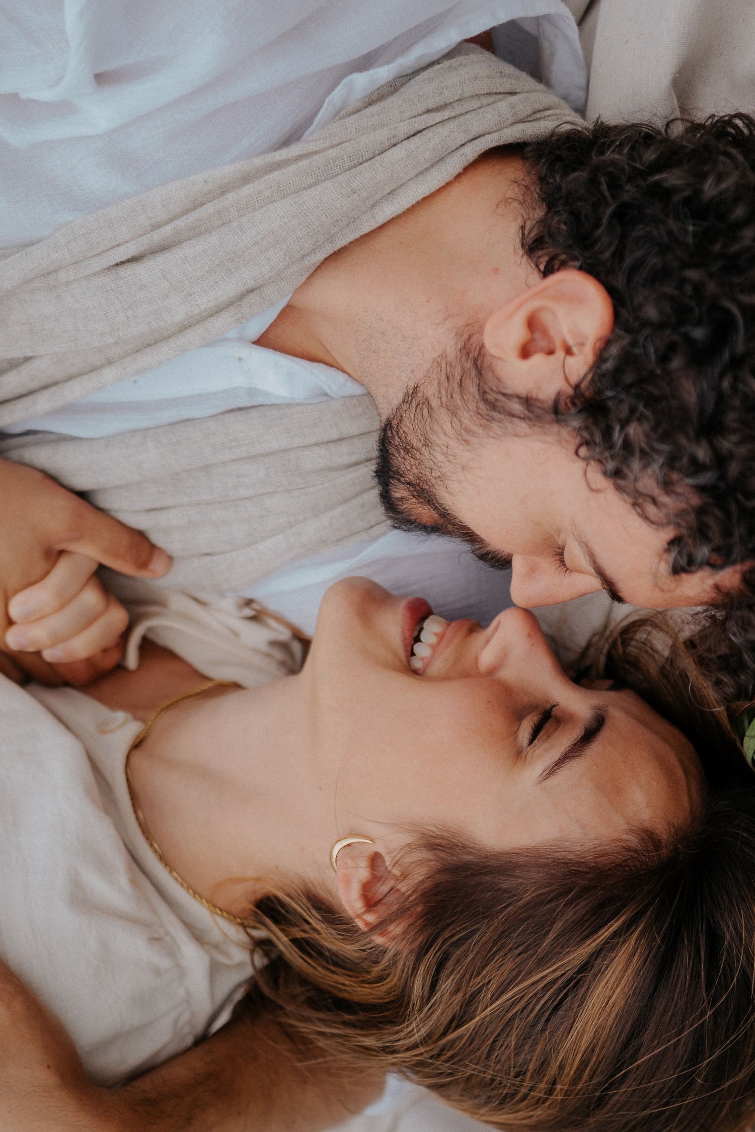 Intimate close-up of couple sharing tender moment on white bedding.