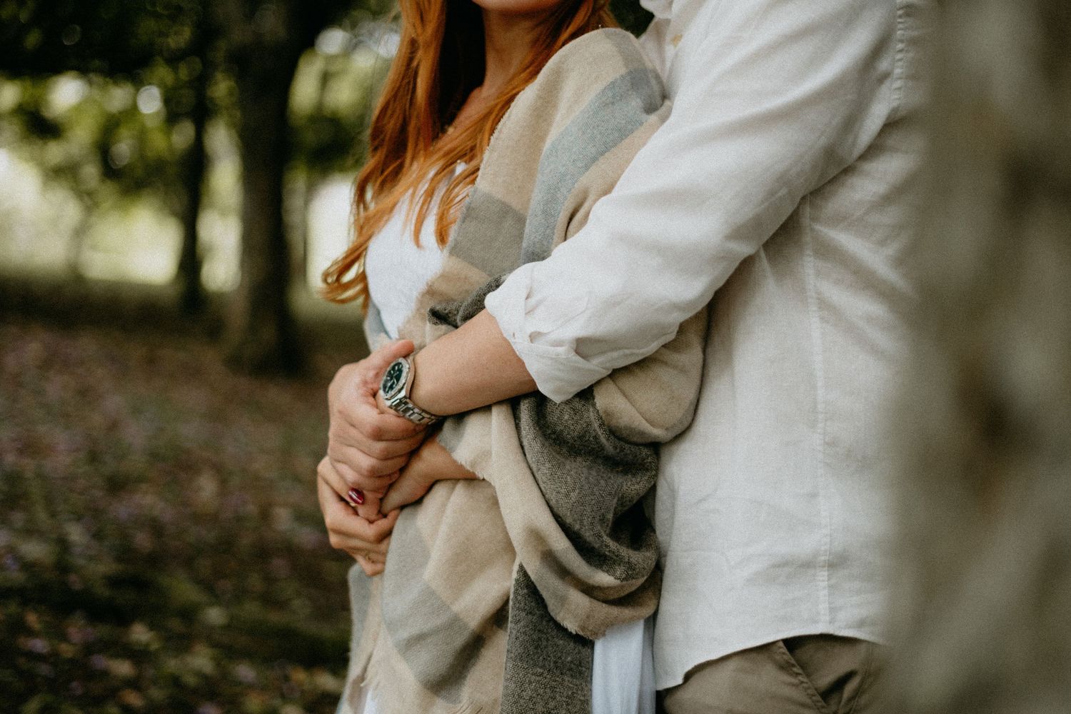 A romantic embrace captured in soft lighting among trees.