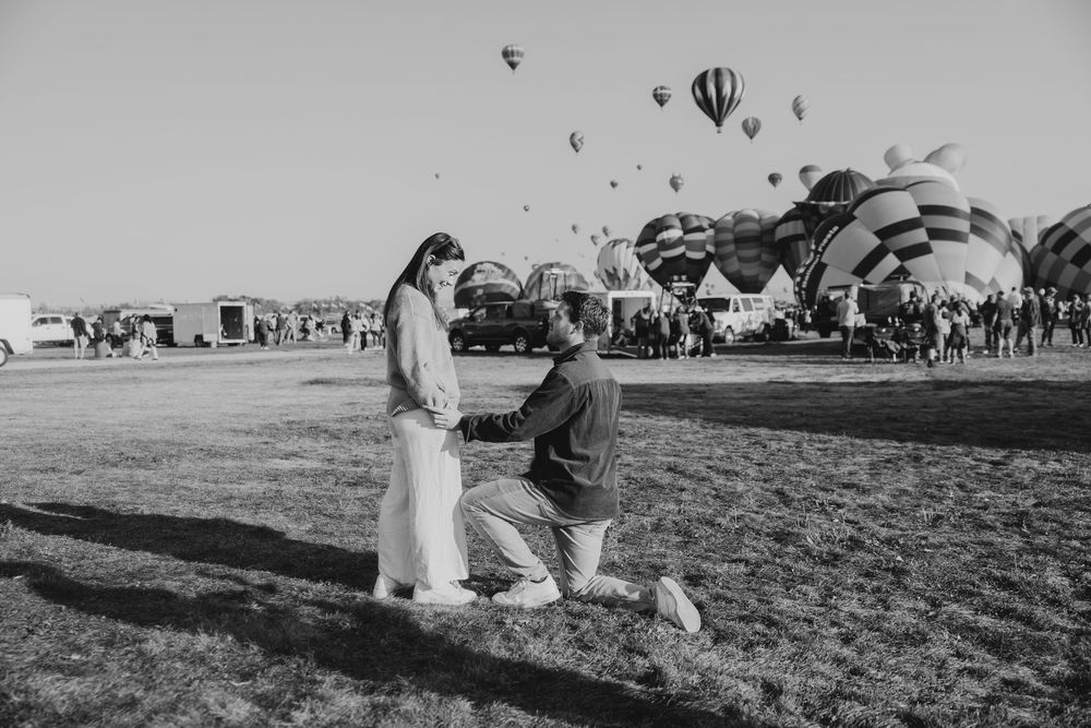Black and white photo of a romantic marriage proposal at a hot air balloon festival.
