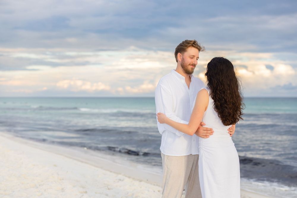 Romantic couple enjoying tender moments on sunny beach during a tropical photography session.