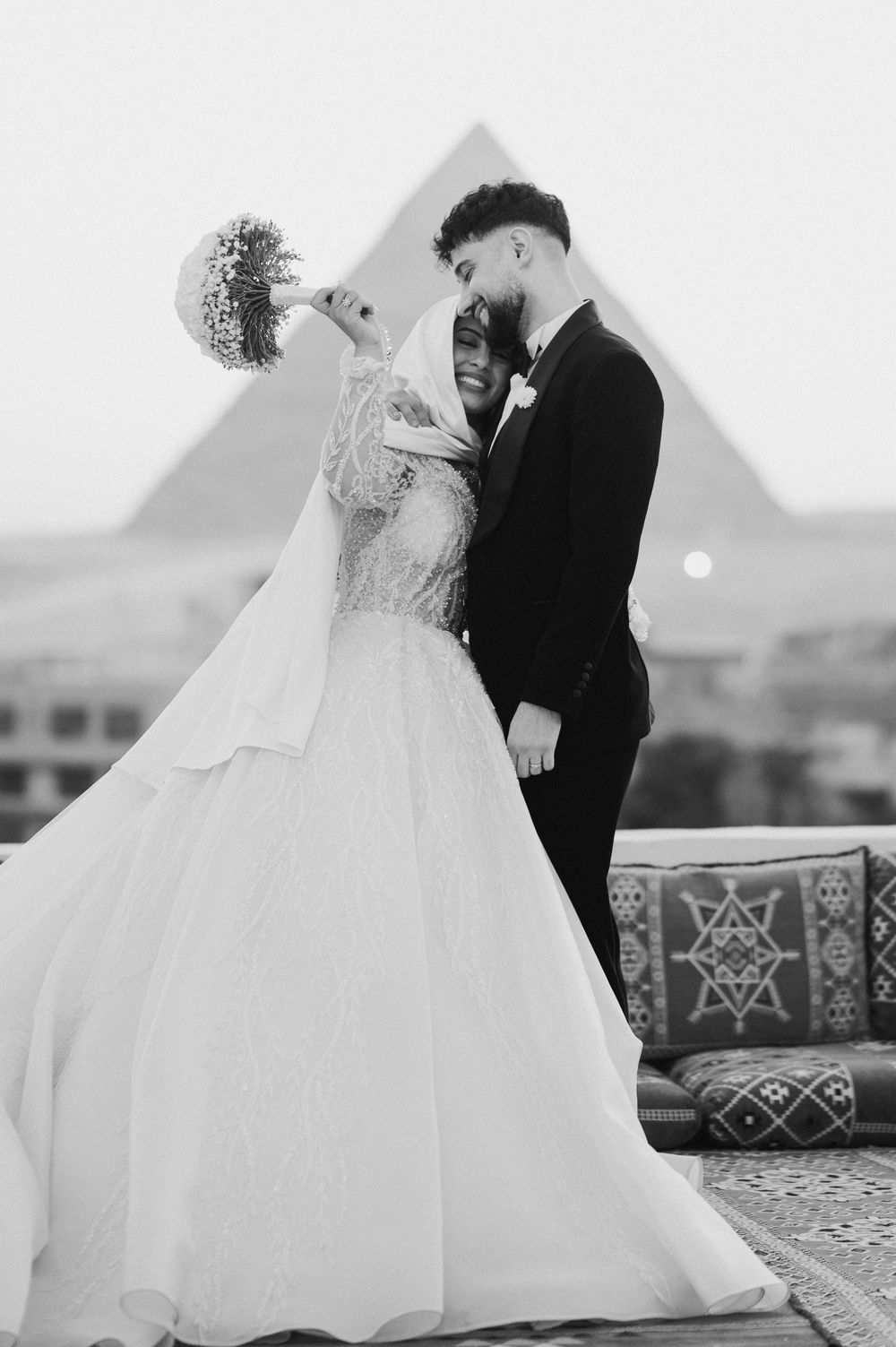 A romantic black and white wedding photoshoot shows couples embracing on a patterned floor with geometric designs outdoors.