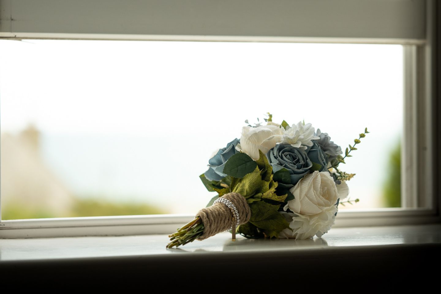 A bridal bouquet, on a window, near Bridport, by Poole, Bournemouth and Dorset wedding photographer "kris the photographer"
