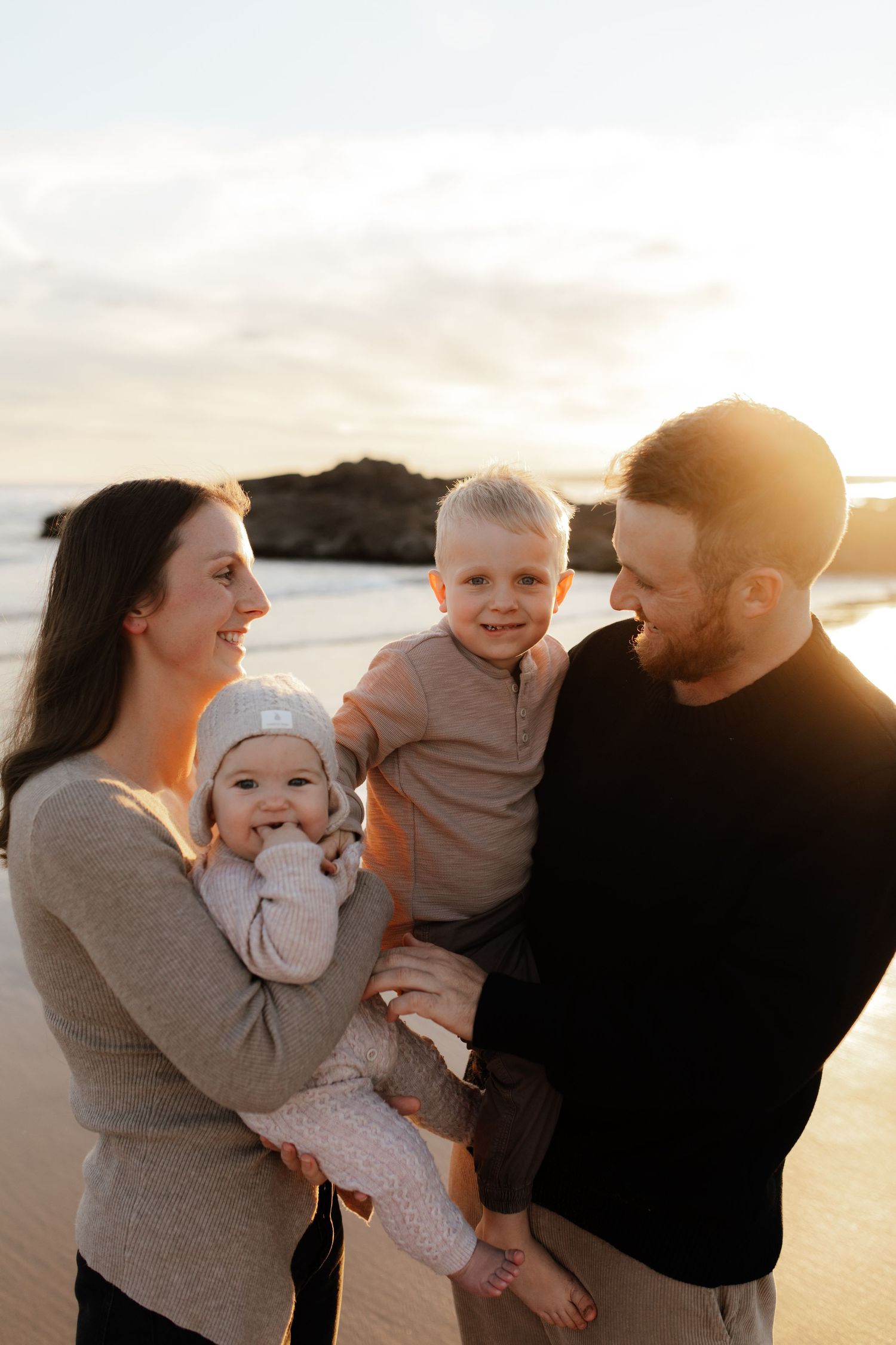 A family shares joyful moments together during a sunset photoshoot at the beach.