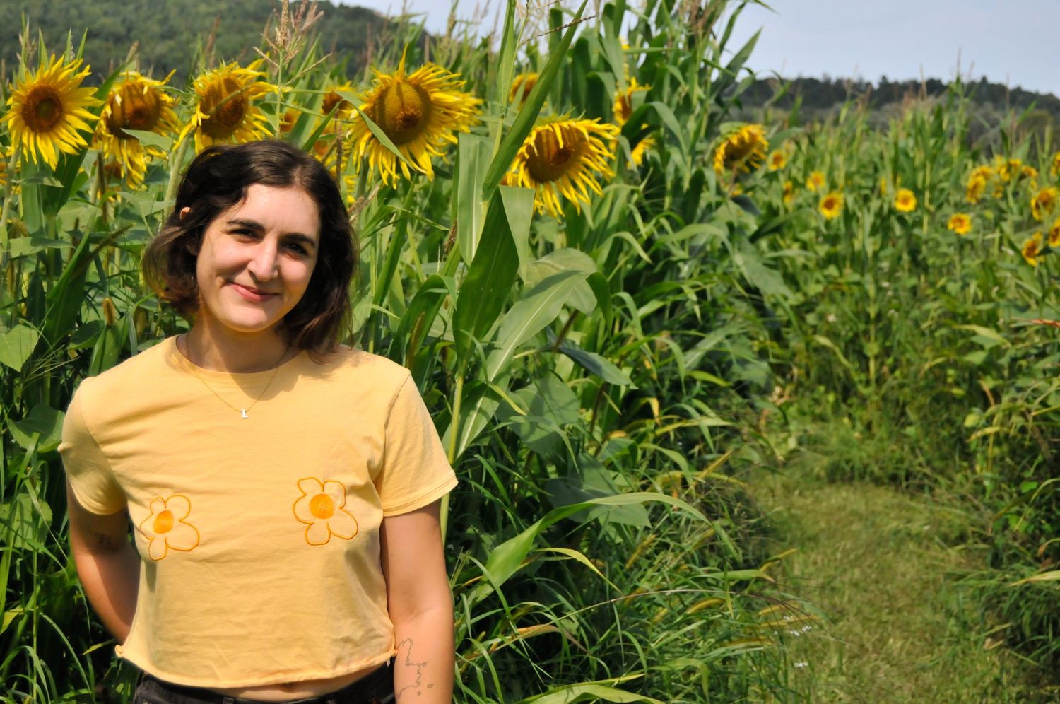 Mother poses in a Vermont country field during an outdoor family photo session.