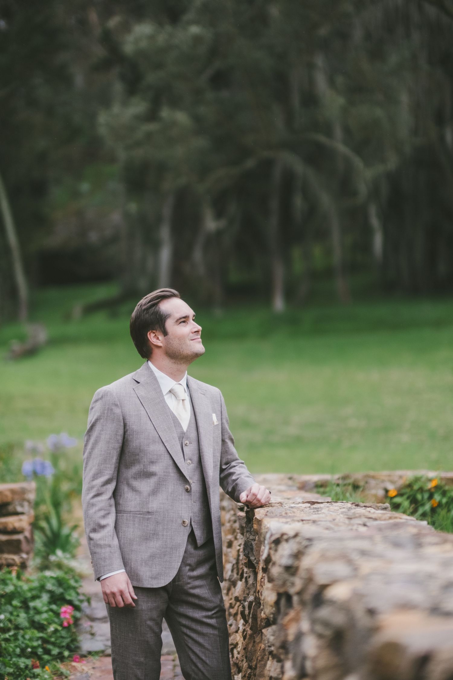 Formal event photography captured in a lush tropical garden setting with a green lawn and palm fronds in the background.