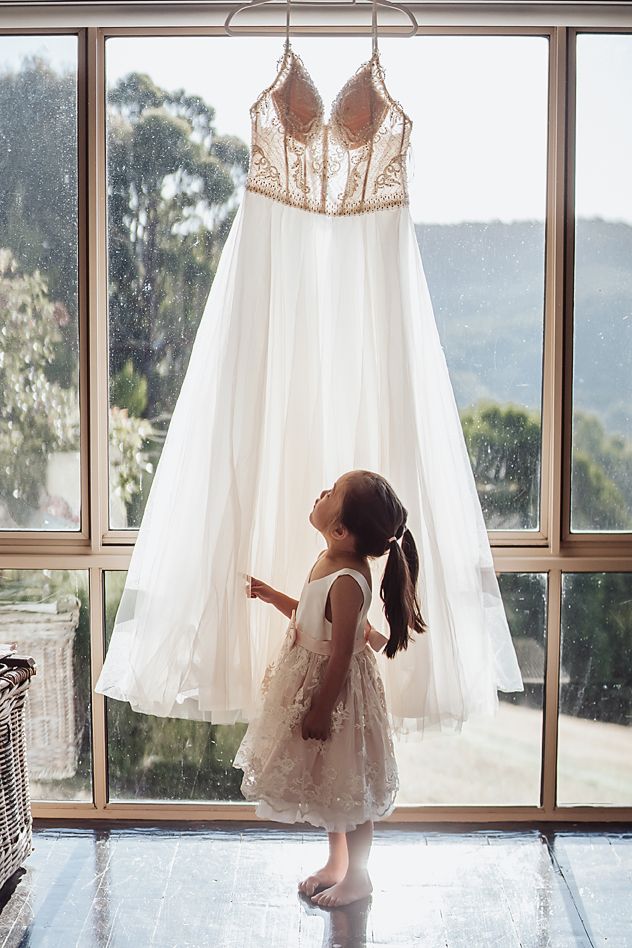 Several elegant white wedding dresses displayed in a bright room with large windows and scenic mountain views.