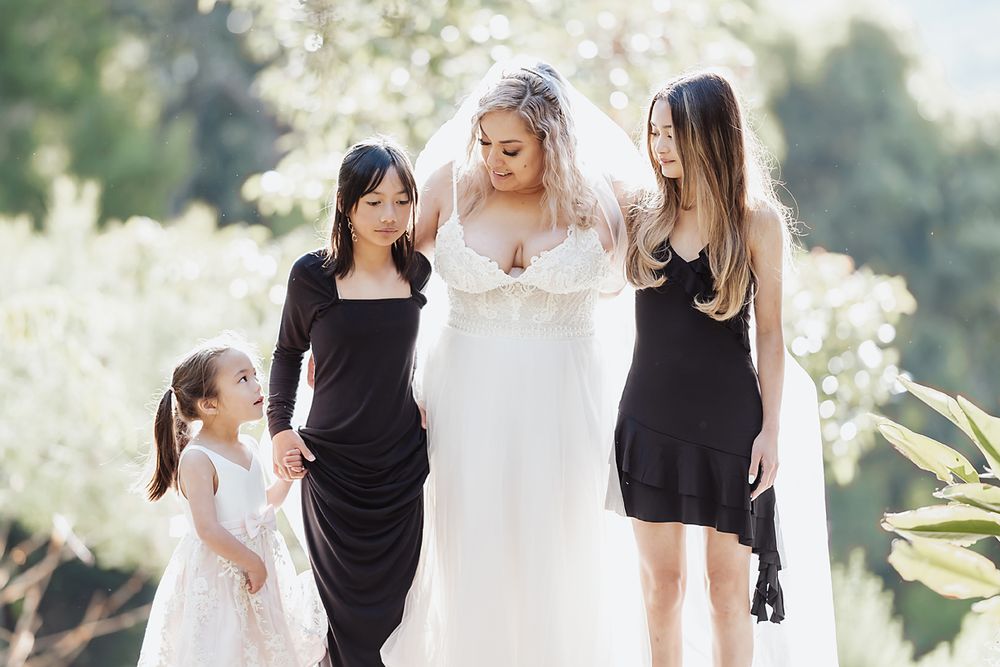 Wedding party in black and white dresses poses together under natural outdoor lighting for formal photos.