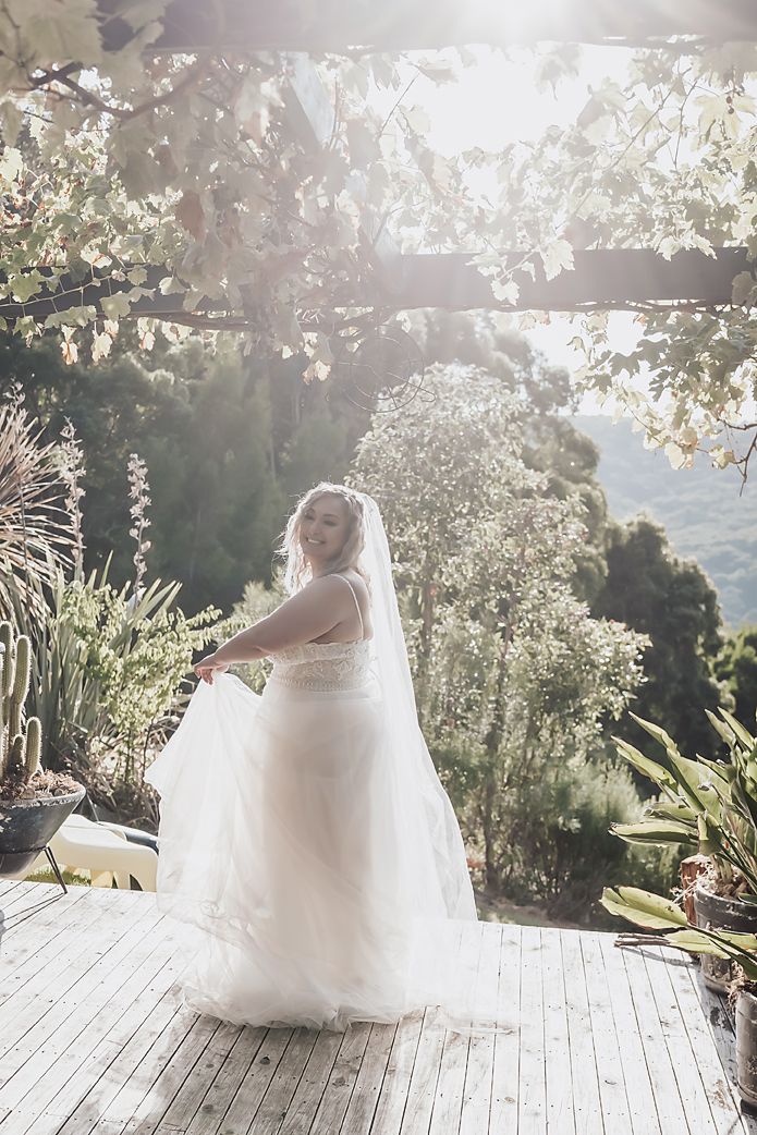 Sunlit outdoor bridal portraits on a wooden deck surrounded by lush greenery and natural light.