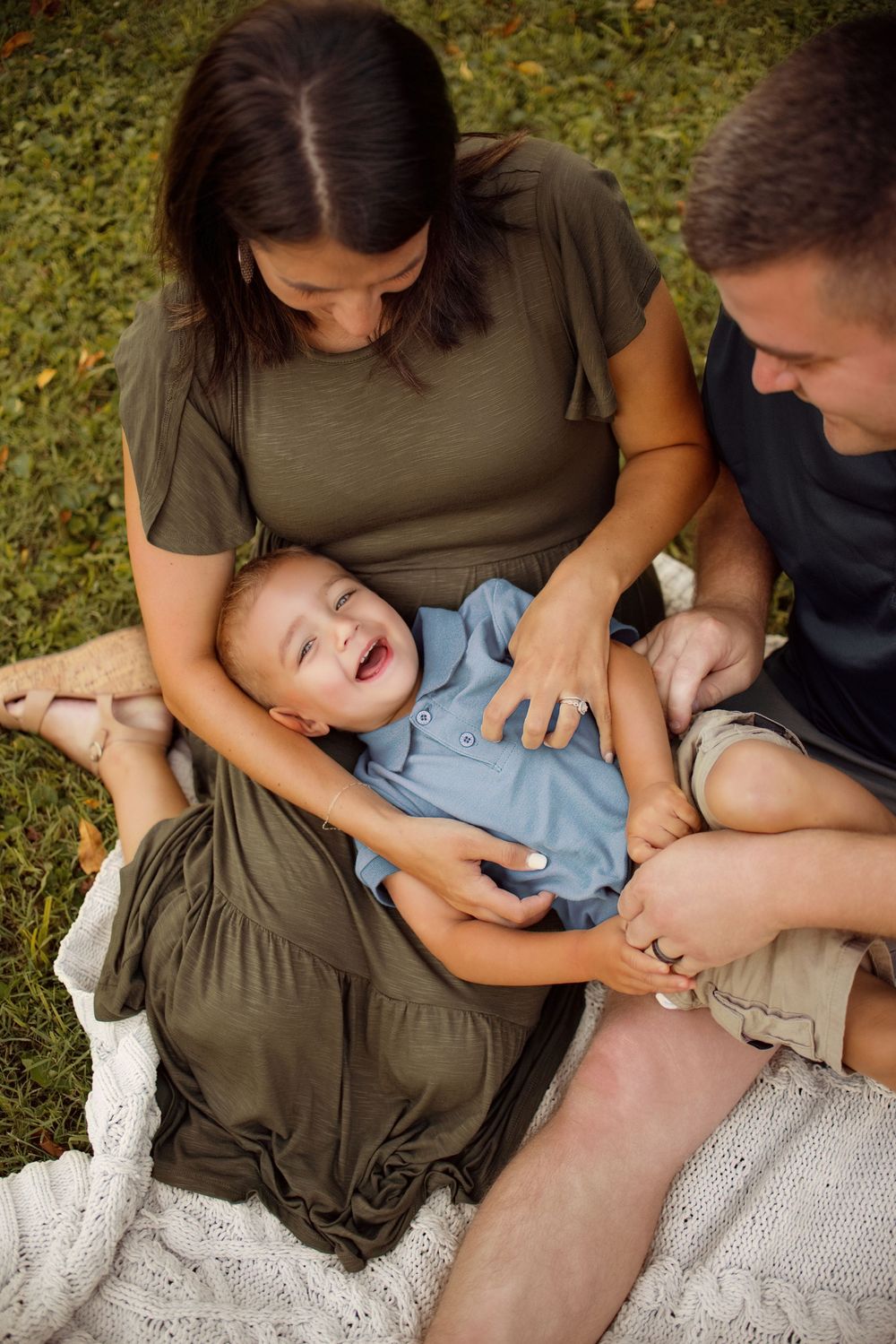 A tender family moment captured in a series of four photos showing parents bonding with a baby on a white blanket outdoors.