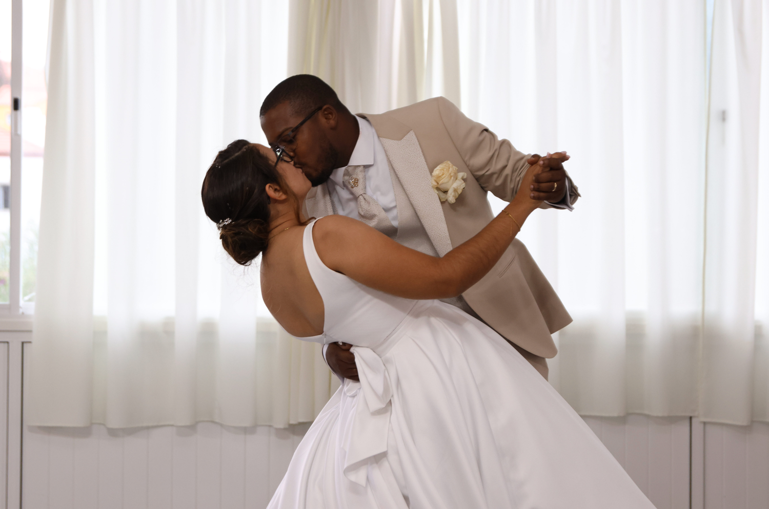 Romantic wedding couple dancing with dramatic dip pose indoors.